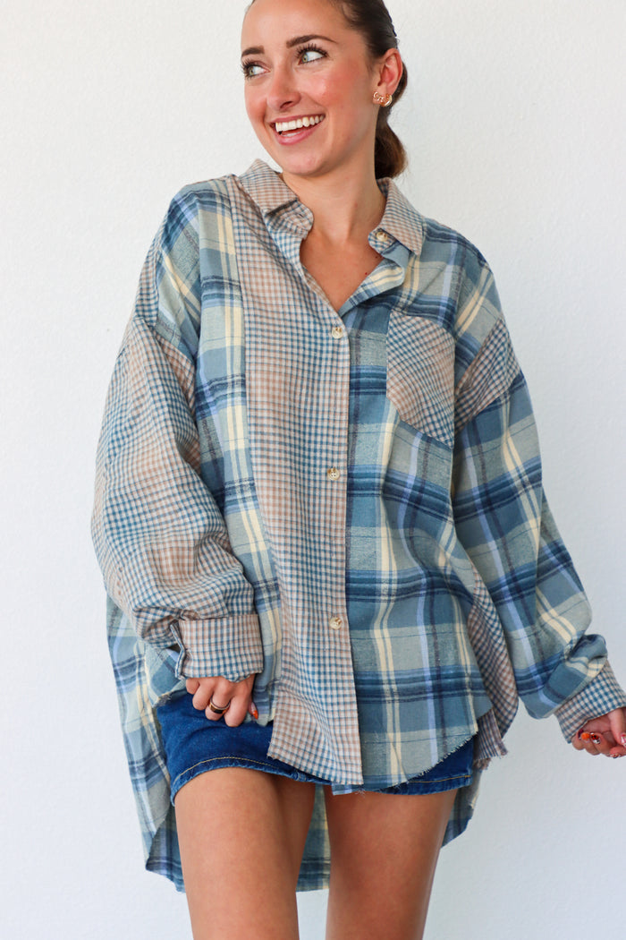 Woman wearing a blue plaid shirt over a denim dress against a white background