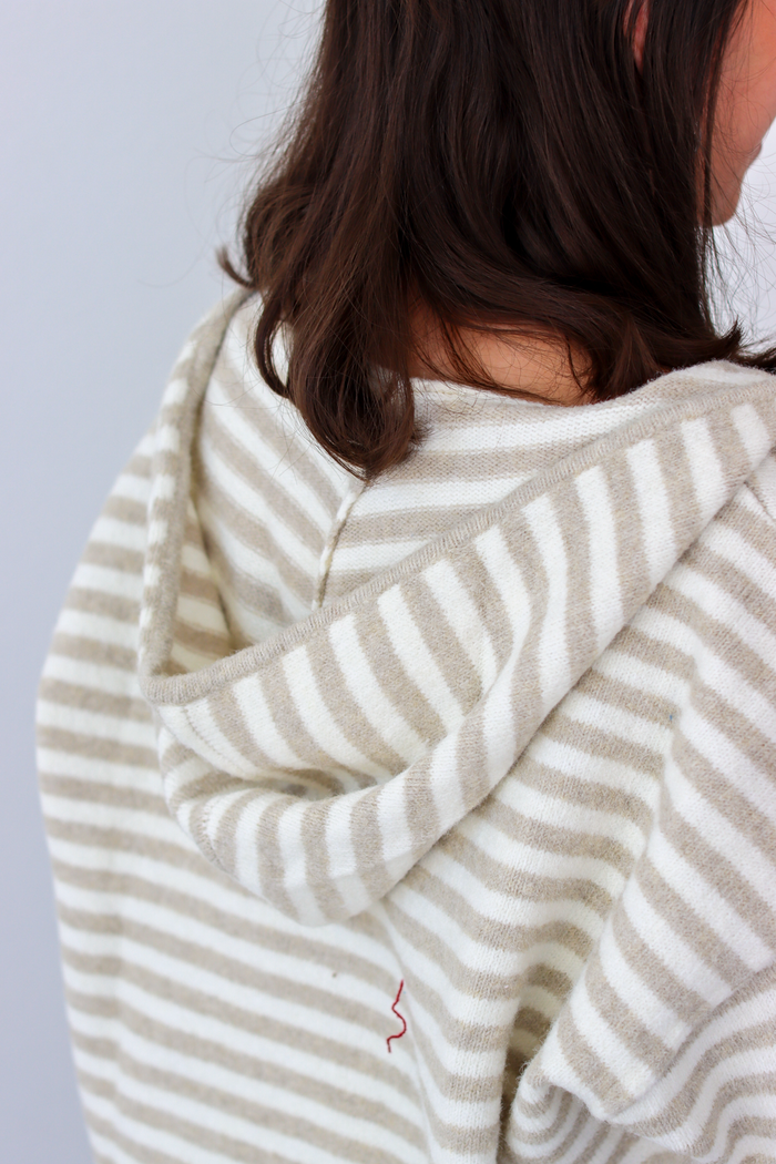 Close up of hood on tan and white stripe zip-up sweater