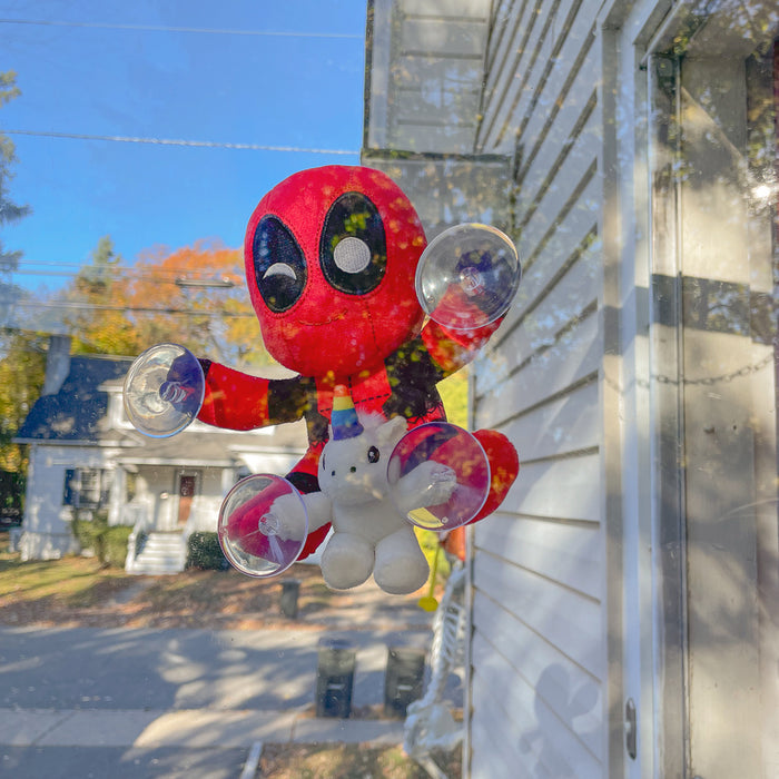 Deadpool with unicorn plush window clinger featuring vibrant colors and playful design, perfect for decorating windows.