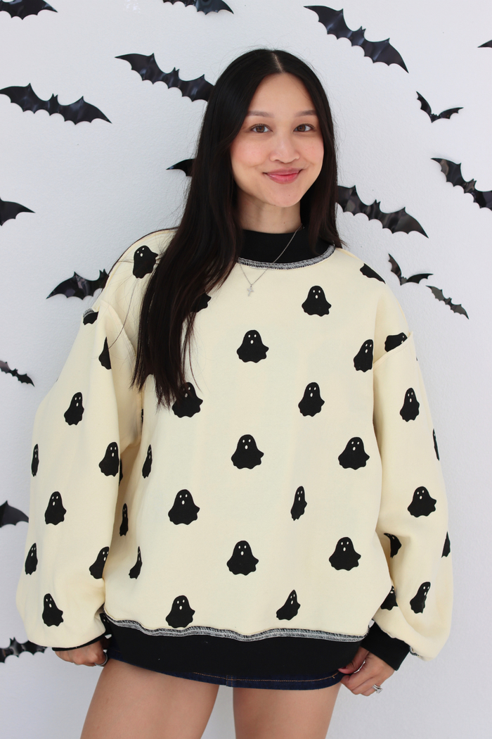 Woman wearing a white sweater with small ghost graphic