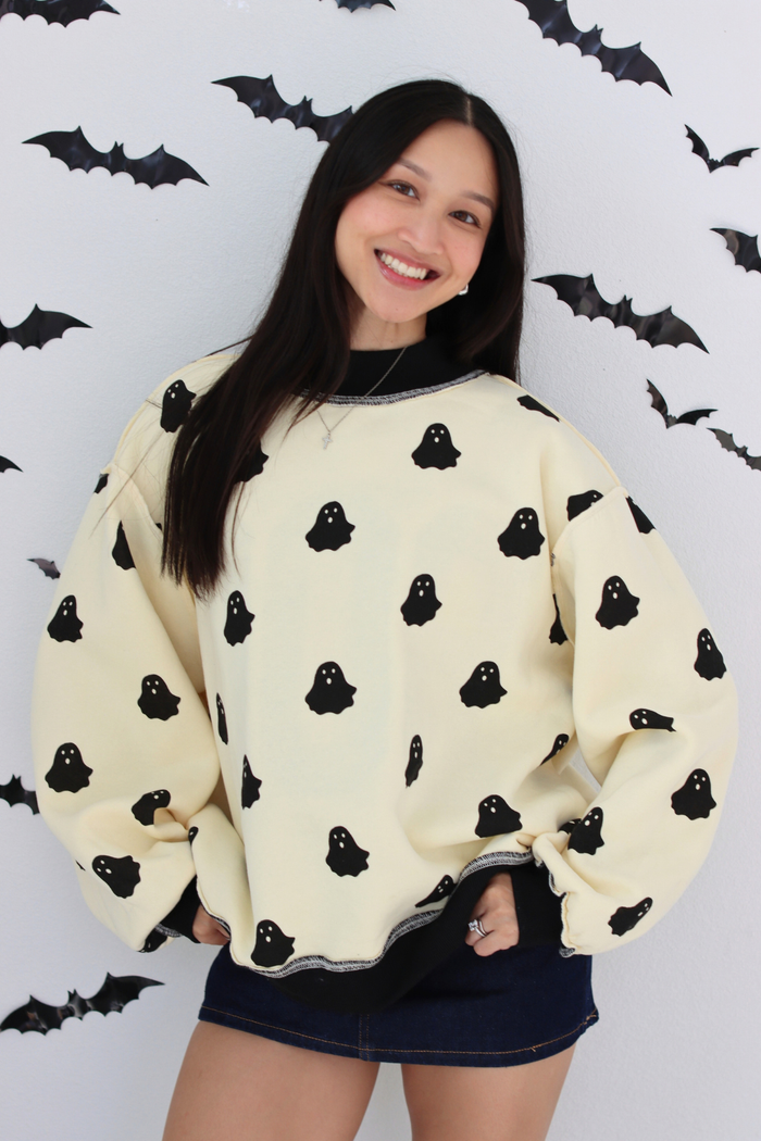 Woman wearing a white sweater with small ghost graphic