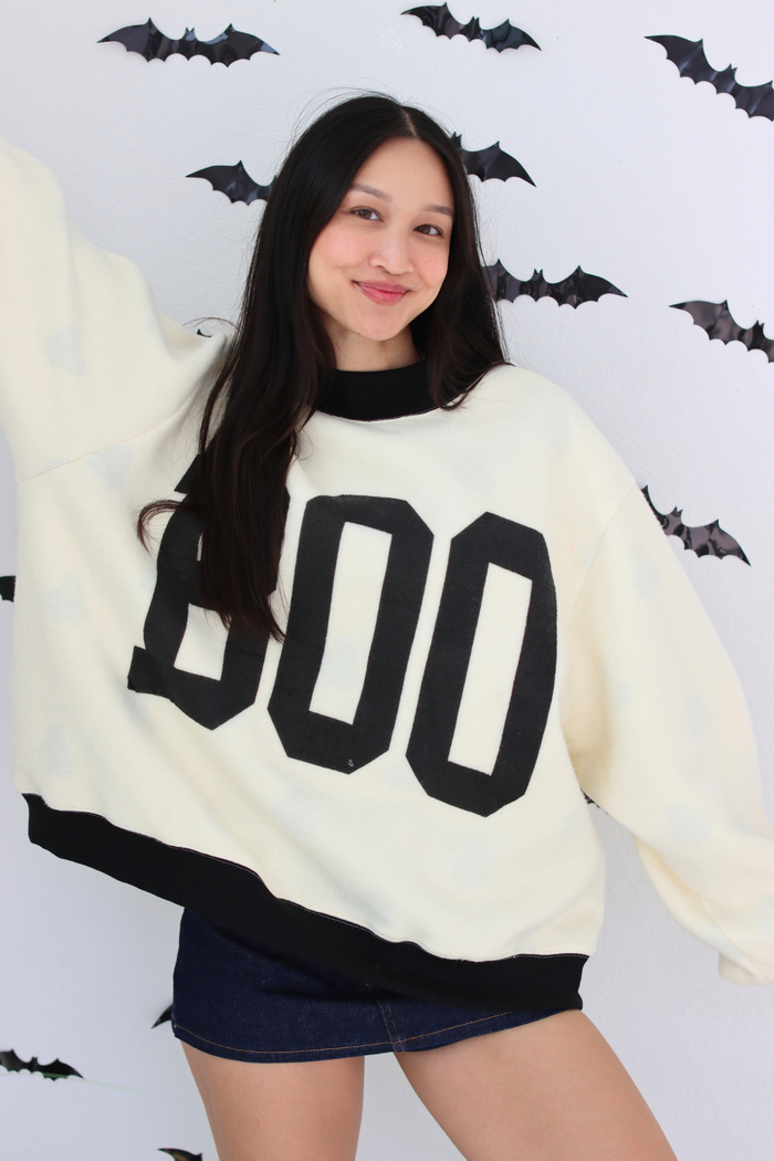 Woman wearing a white sweater with BOO graphic