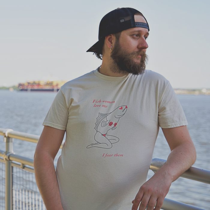 Model wearing Sirena (Fish Woman) T-Shirt from Cryptid Records in natural, at a riverside railing
