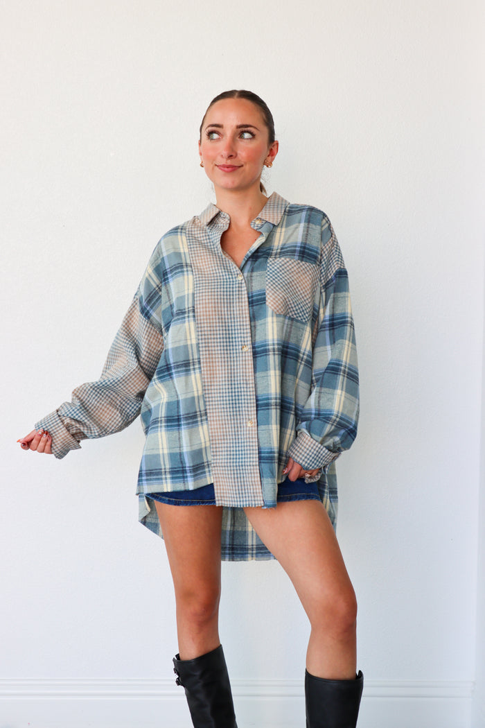 Woman wearing a blue and white plaid shirt dress with black boots against a white background